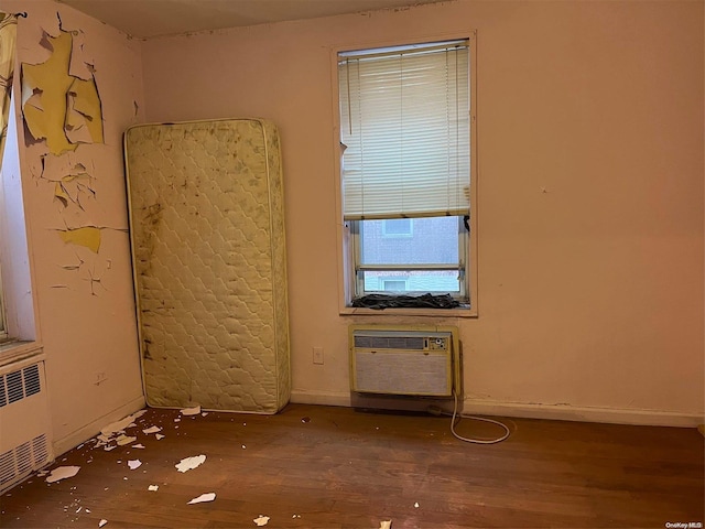 empty room with an AC wall unit and dark wood-type flooring