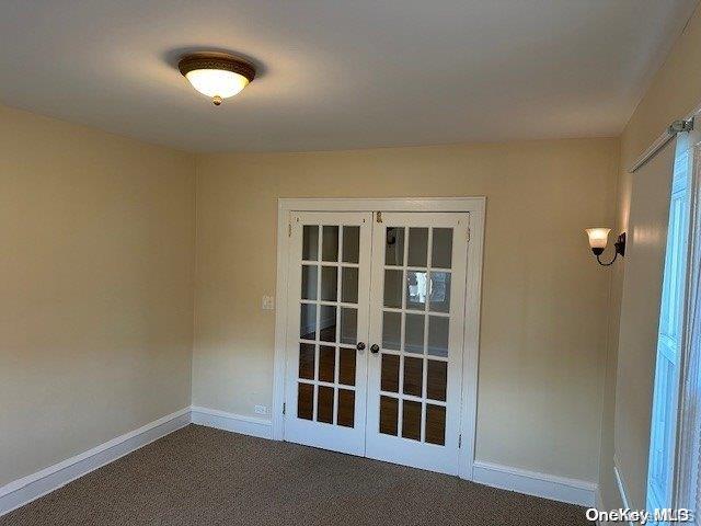 carpeted spare room featuring french doors