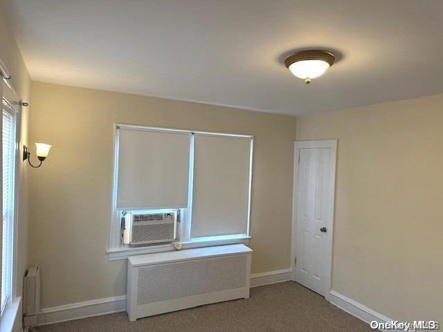 carpeted spare room with cooling unit and radiator