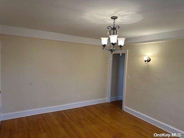 unfurnished room with wood-type flooring and an inviting chandelier