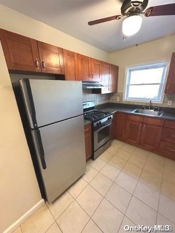 kitchen with appliances with stainless steel finishes, backsplash, exhaust hood, sink, and light tile patterned floors