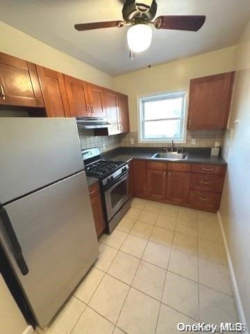 kitchen featuring tasteful backsplash, sink, light tile patterned floors, and appliances with stainless steel finishes