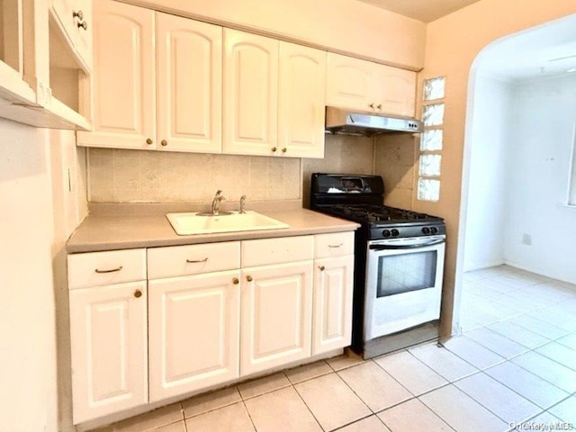 kitchen featuring backsplash, sink, light tile patterned floors, gas range gas stove, and white cabinetry