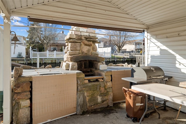 view of patio featuring a water view and an outdoor stone fireplace