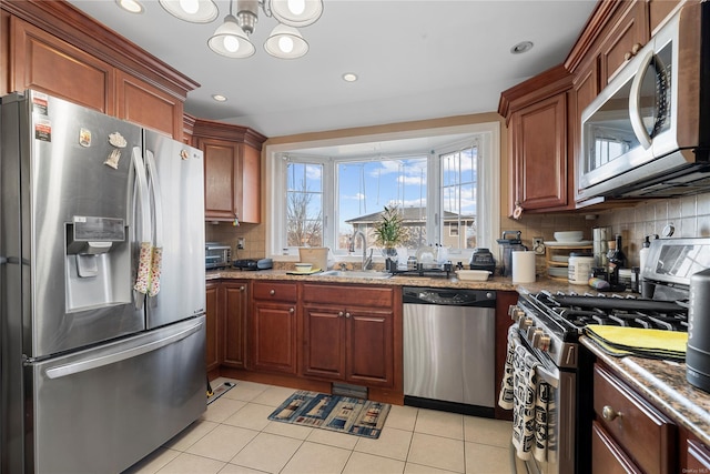 kitchen featuring light tile patterned flooring, appliances with stainless steel finishes, sink, and backsplash