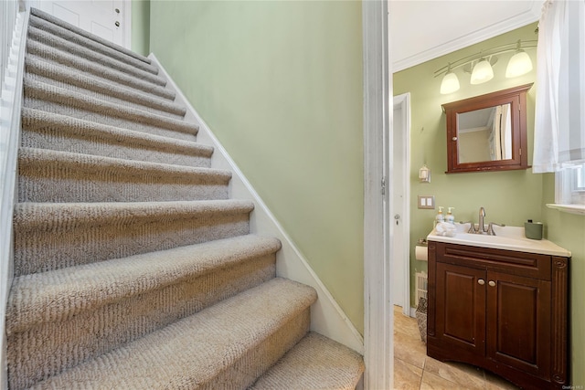 staircase with crown molding, tile patterned floors, and sink