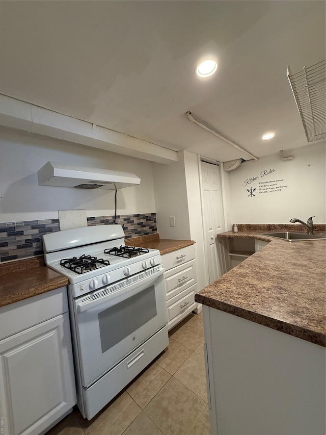 kitchen with light tile patterned flooring, white cabinetry, sink, decorative backsplash, and white gas stove