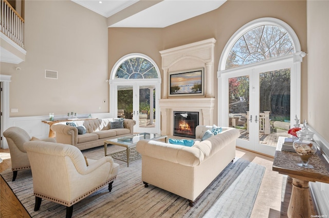 living room with light hardwood / wood-style floors, a towering ceiling, and french doors