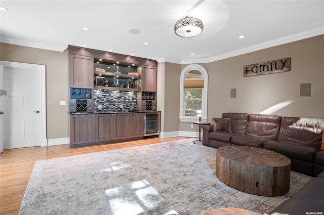 living room featuring bar, crown molding, beverage cooler, and light hardwood / wood-style floors