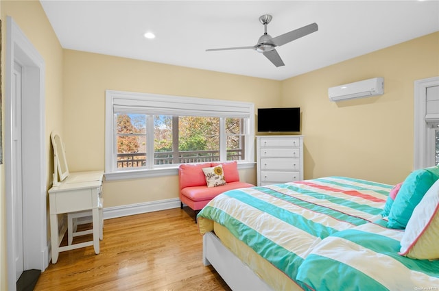 bedroom featuring an AC wall unit, ceiling fan, and light hardwood / wood-style floors