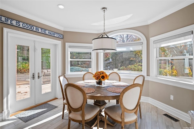 dining space with crown molding, french doors, and light wood-type flooring