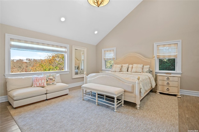 bedroom with multiple windows, light hardwood / wood-style flooring, and high vaulted ceiling