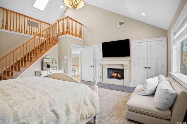 bedroom featuring hardwood / wood-style flooring, high vaulted ceiling, and a chandelier