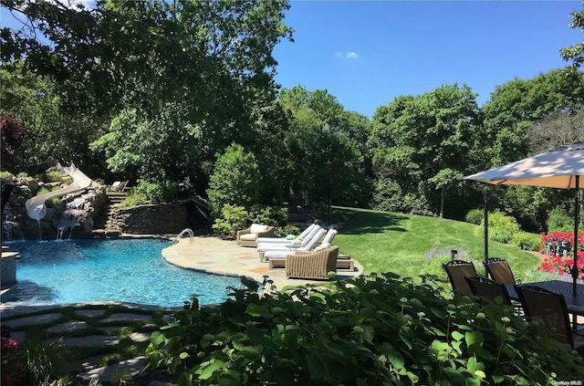 view of pool with a lawn, a water slide, and a patio