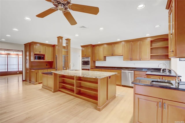 kitchen with ceiling fan, light hardwood / wood-style flooring, an island with sink, and appliances with stainless steel finishes