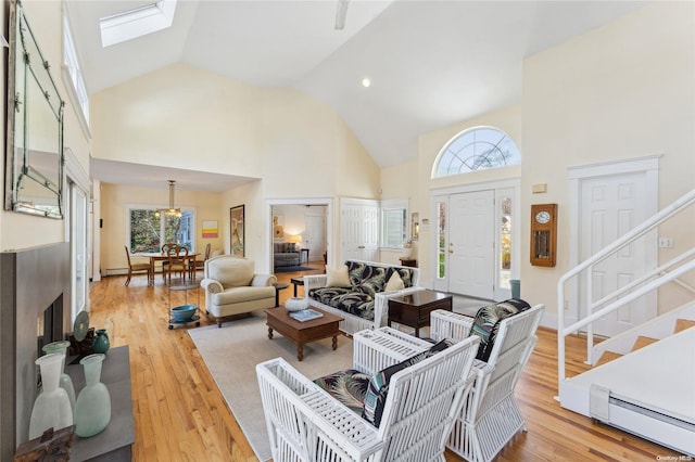 living room featuring a skylight, light hardwood / wood-style flooring, and high vaulted ceiling