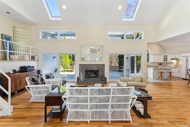 living room featuring a healthy amount of sunlight, light hardwood / wood-style floors, high vaulted ceiling, and a skylight