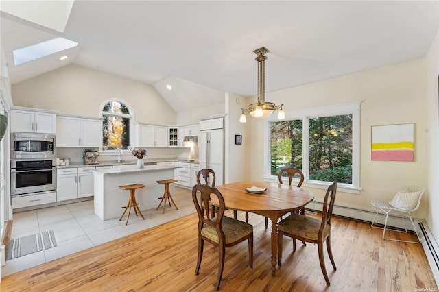 dining space featuring light wood-type flooring, lofted ceiling with skylight, and sink