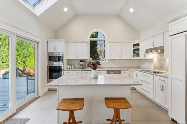 kitchen with appliances with stainless steel finishes, light stone counters, plenty of natural light, and a kitchen breakfast bar