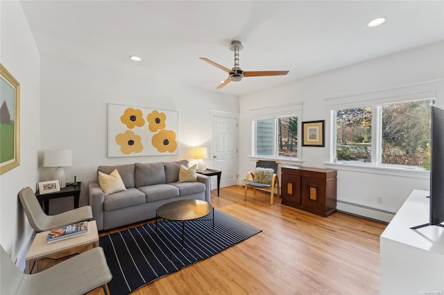 living room featuring light hardwood / wood-style floors, baseboard heating, and ceiling fan