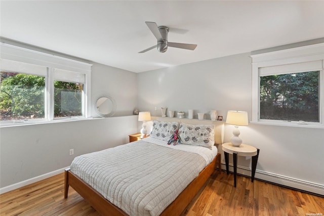 bedroom featuring wood-type flooring, baseboard heating, and ceiling fan