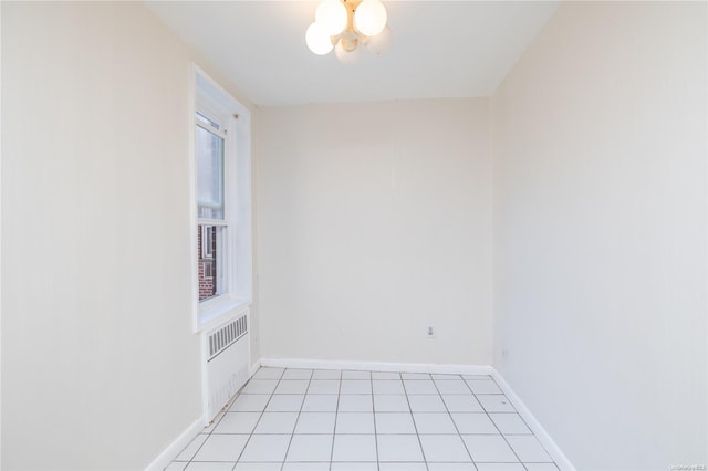 empty room with a chandelier, light tile patterned floors, and radiator