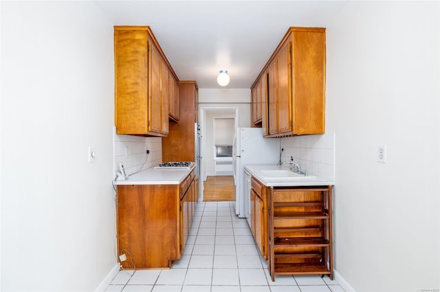 kitchen with light tile patterned floors, tasteful backsplash, stainless steel gas cooktop, and sink