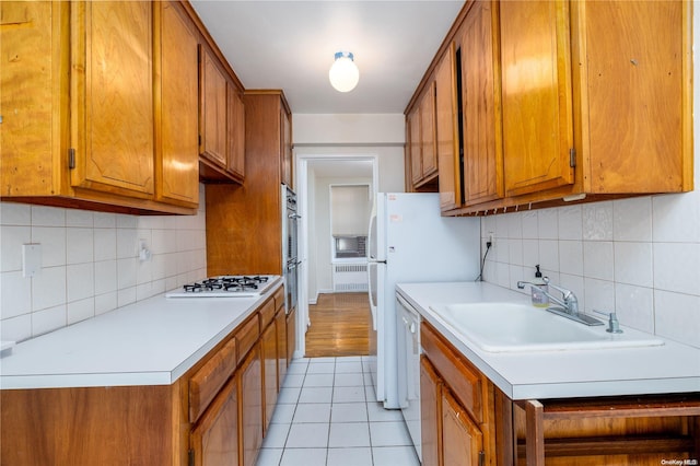 kitchen featuring backsplash, sink, light tile patterned flooring, and white appliances