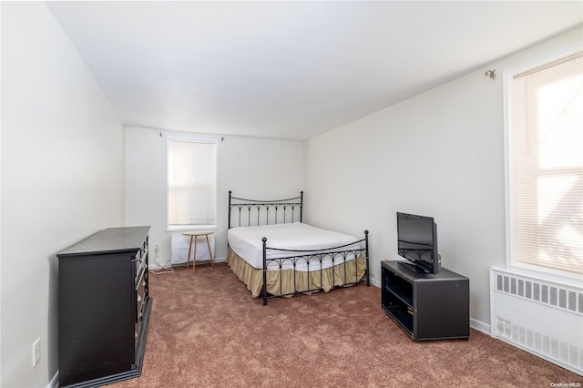 bedroom with multiple windows, dark carpet, and radiator