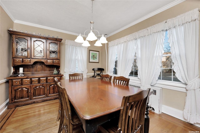 dining area featuring a chandelier, ornamental molding, a wealth of natural light, and light hardwood / wood-style flooring