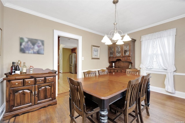 dining space featuring light hardwood / wood-style flooring, crown molding, and a notable chandelier