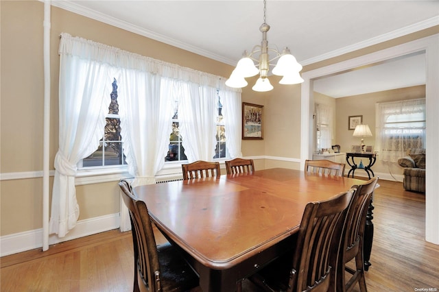 dining space with ornamental molding, a notable chandelier, and light wood-type flooring