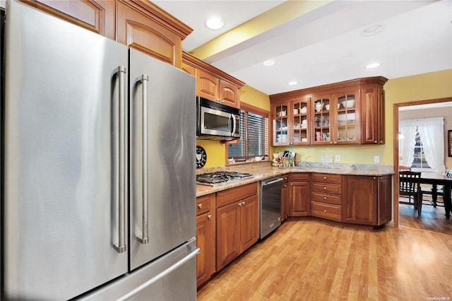 kitchen featuring light stone countertops, light wood-type flooring, and appliances with stainless steel finishes