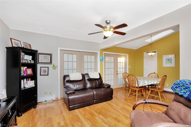 living room featuring vaulted ceiling with skylight, ceiling fan, french doors, and hardwood / wood-style flooring