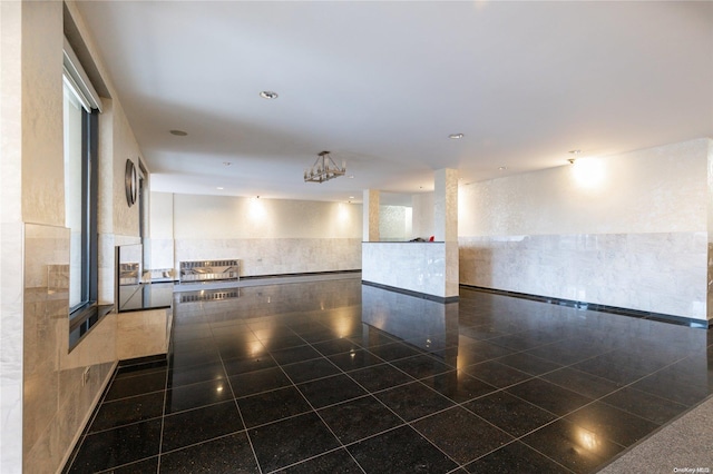 empty room with dark tile patterned floors and tile walls