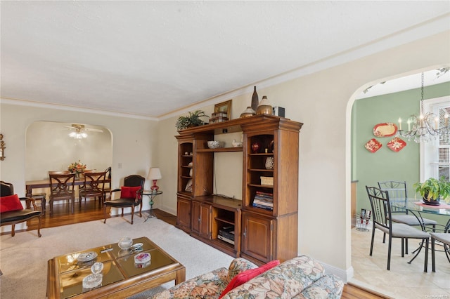 living room featuring ceiling fan with notable chandelier, light wood-type flooring, and ornamental molding