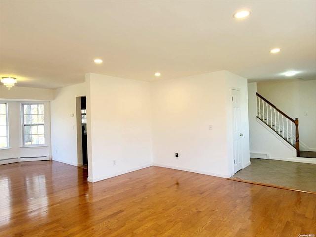 spare room featuring baseboard heating and hardwood / wood-style flooring