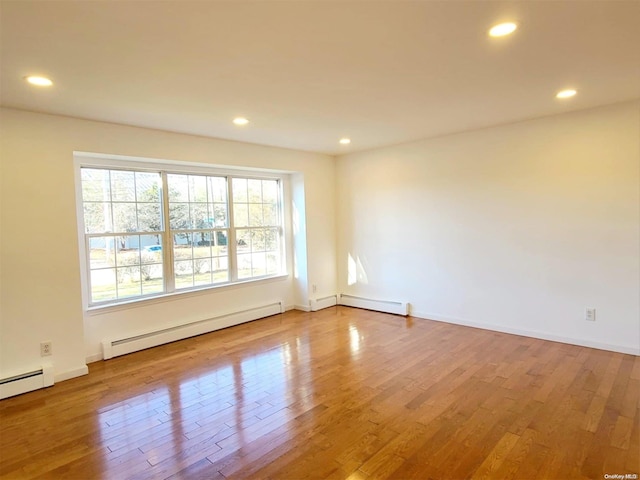 spare room with wood-type flooring and a baseboard heating unit