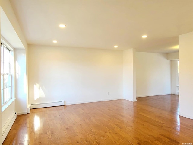 empty room featuring baseboard heating and light hardwood / wood-style floors