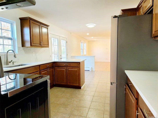 kitchen with stainless steel refrigerator, sink, a baseboard radiator, kitchen peninsula, and light tile patterned floors