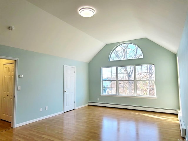 unfurnished living room featuring vaulted ceiling, light wood-type flooring, a wealth of natural light, and a baseboard radiator