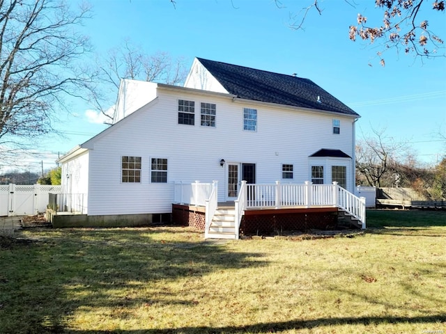 back of property with a deck and a lawn