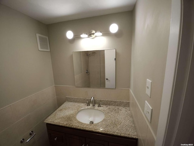 bathroom featuring vanity and tile walls