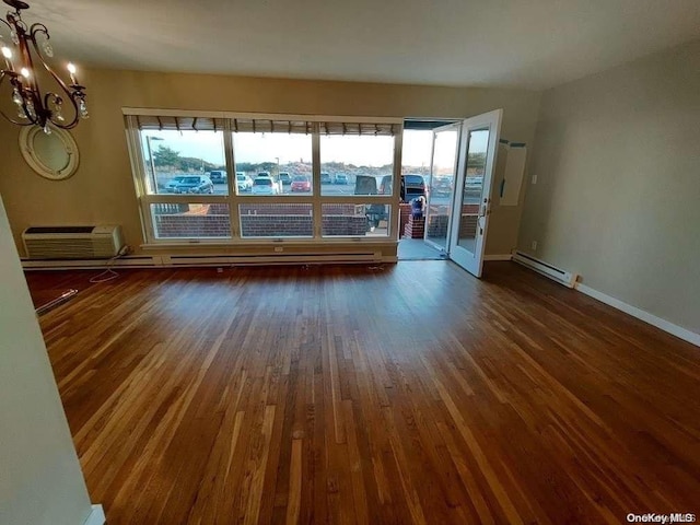 unfurnished room featuring an inviting chandelier, an AC wall unit, dark wood-type flooring, and a baseboard radiator