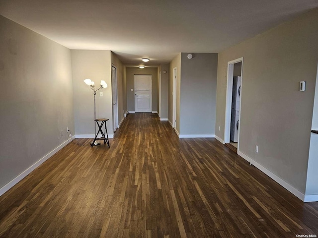 spare room featuring stacked washer and dryer and dark wood-type flooring