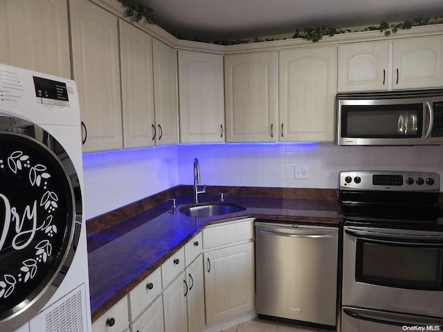 kitchen featuring tasteful backsplash, stainless steel appliances, sink, light tile patterned floors, and washer / clothes dryer