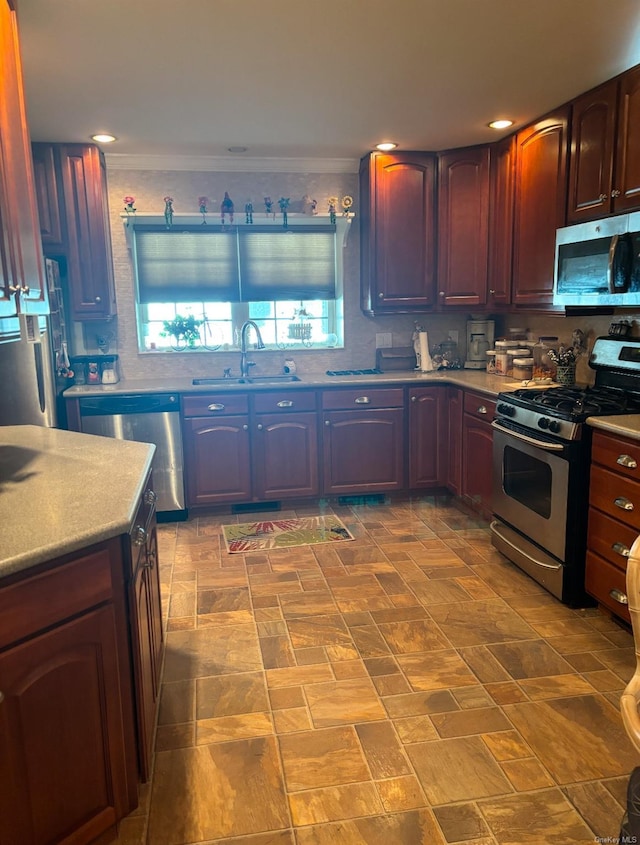 kitchen with appliances with stainless steel finishes, crown molding, and sink