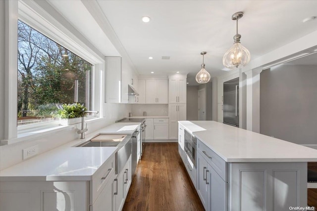 kitchen with white cabinets, plenty of natural light, sink, and hanging light fixtures