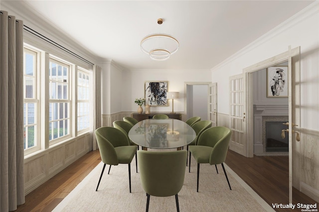 dining area with hardwood / wood-style floors, crown molding, and a fireplace