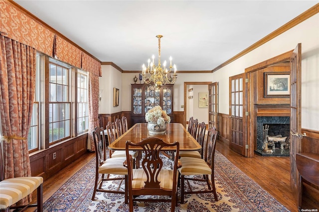 dining area featuring hardwood / wood-style floors, a premium fireplace, ornamental molding, and an inviting chandelier